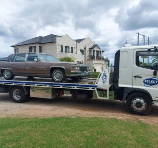 A Classic Cadillac being towed by a reliable transport truck