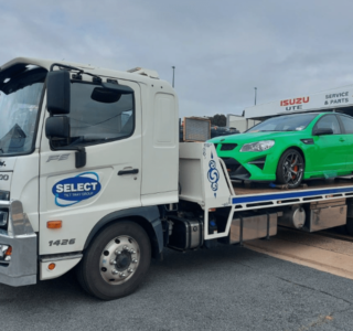 A green Holden HSV performance car being transported by tow truck.