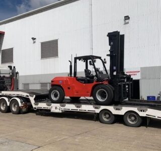 A forklift being transported on a low loader trailer